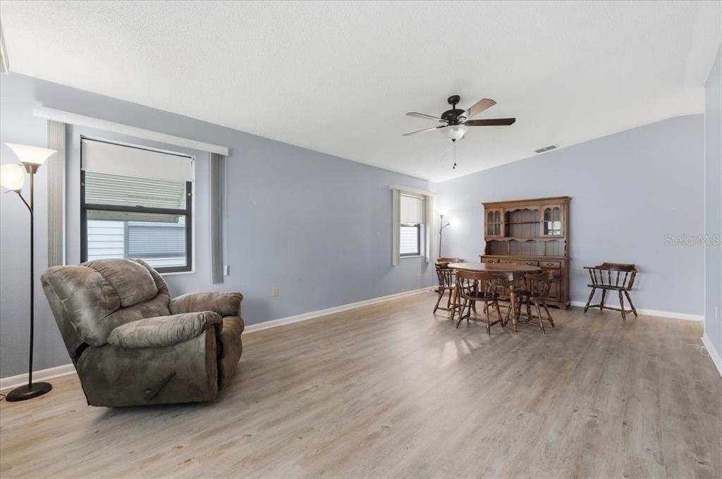 A living and dining area features light blue walls, wood-look flooring, and a ceiling fan — 3231 BEAR CREEK LANE, LAKELAND, FL
