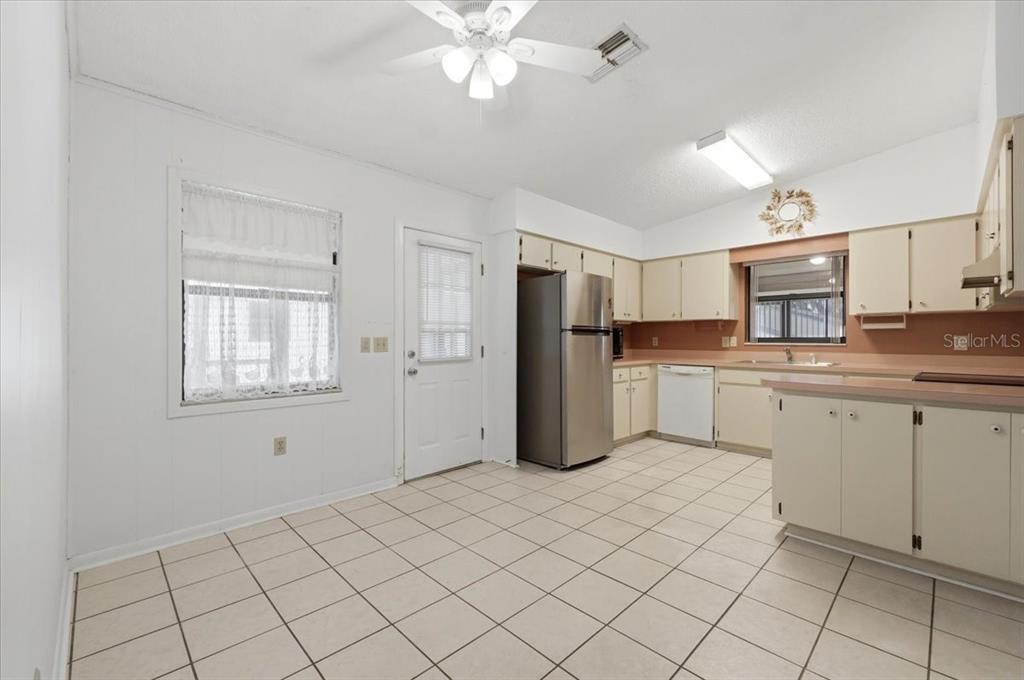 A kitchen with white tile floors, light-colored cabinets, a stainless steel refrigerator, and a ceiling fan — 3231 BEAR CREEK LANE, LAKELAND, FL