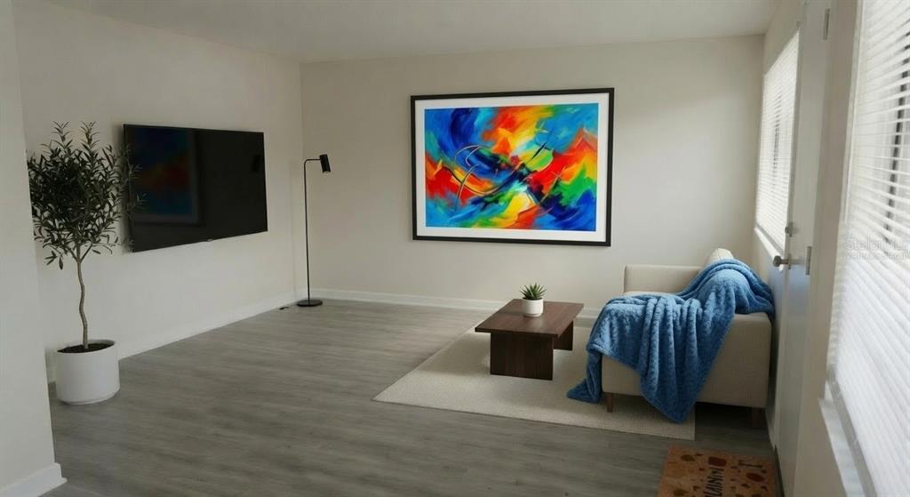 A living room features light wood-look flooring, a wall-mounted television, and a colorful abstract painting — 8100 DR MARTIN LUTHER KING JR STREET N UNIT 105, ST PETERSBURG, FL