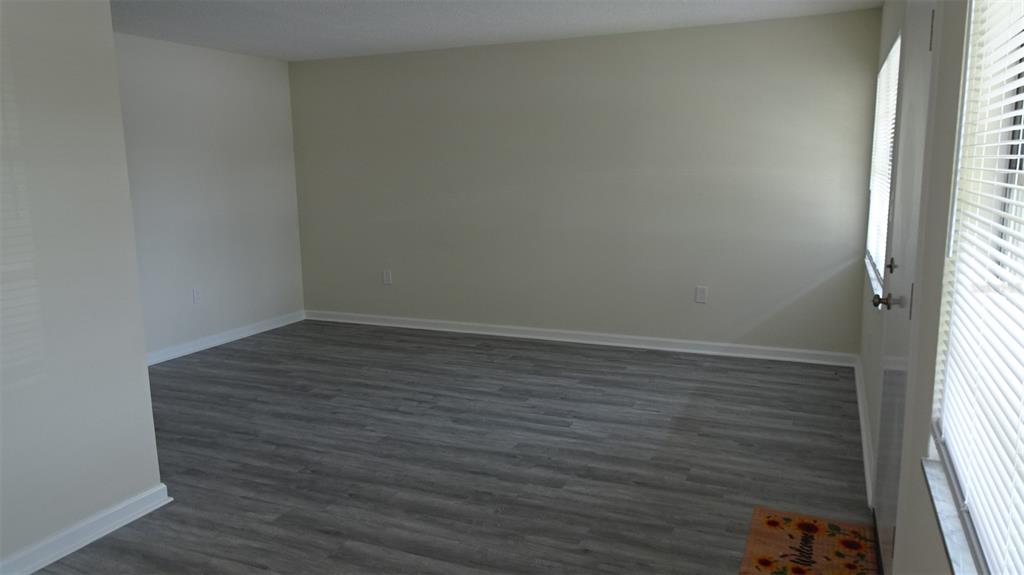 An empty room with light-colored walls, gray wood-look flooring, and a window with blinds — 8100 DR MARTIN LUTHER KING JR STREET N UNIT 105, ST PETERSBURG, FL