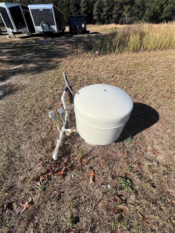 A beige well pressure tank sits on the ground outdoors near some trailers — 26 PINE RUN, OCALA, FL