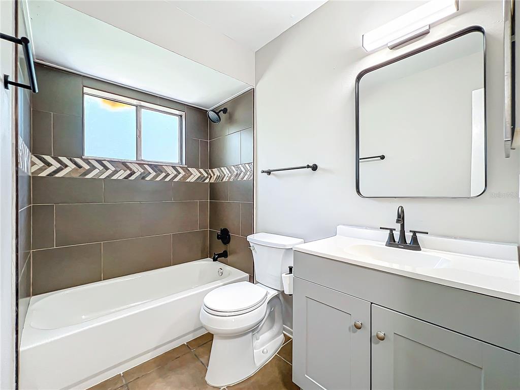 A bathroom features a gray vanity, a white toilet, and a tiled tub-shower combination — 13868 LENA STREET, ORLANDO, FL