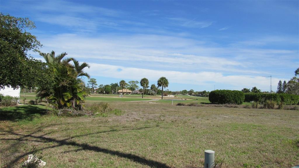 A vacant grassy lot overlooks a golf course with palm trees under a blue sky — 2064 LITTLE PINE CIRCLE, PUNTA GORDA, FL