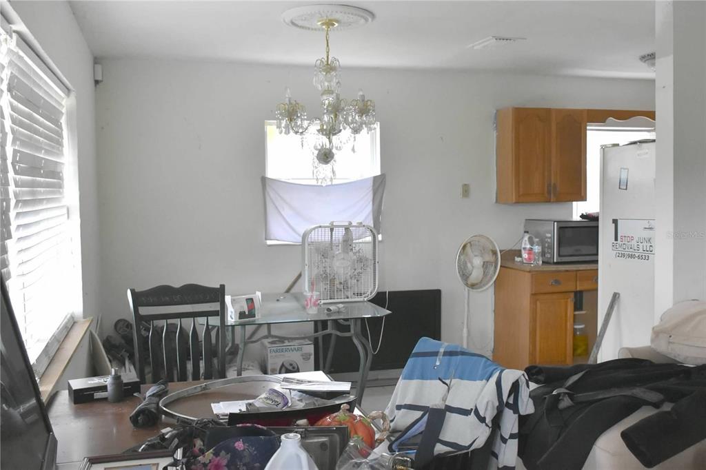 A dining area features a crystal chandelier, a glass table, and an adjacent kitchen space — 907 PINE STREET, IMMOKALEE, FL