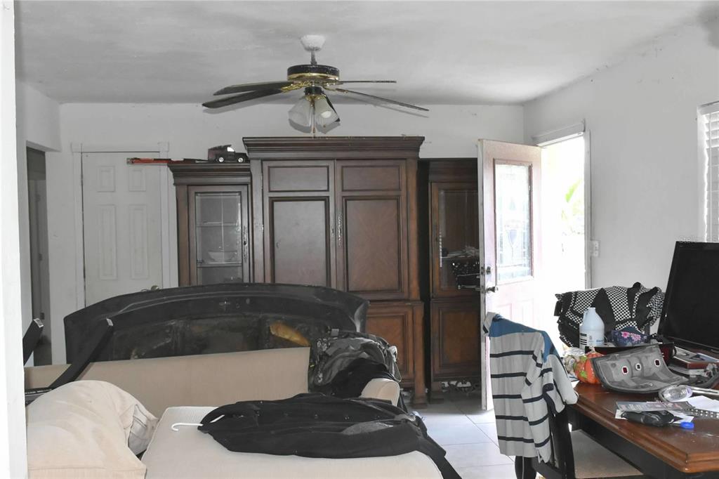 A living room features a large wooden cabinet, a ceiling fan, and a desk area — 907 PINE STREET, IMMOKALEE, FL