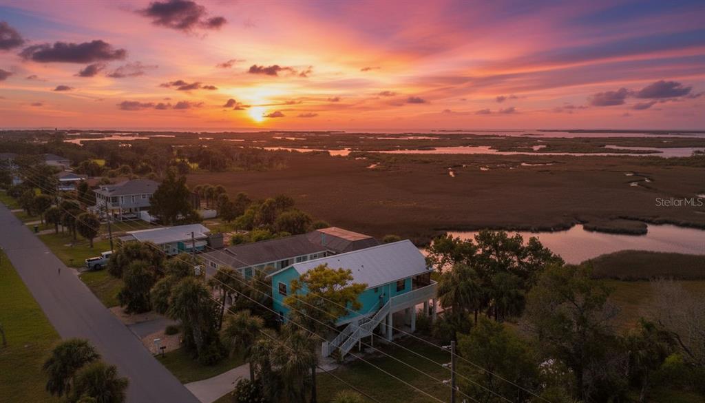 An aerial view of a teal house situated next to a marsh at sunset — 4035 EAGLE NEST DRIVE, HERNANDO BEACH, FL
