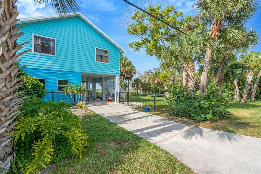 A bright blue elevated house with a concrete driveway and palm trees in the yard — 4035 EAGLE NEST DRIVE, HERNANDO BEACH, FL