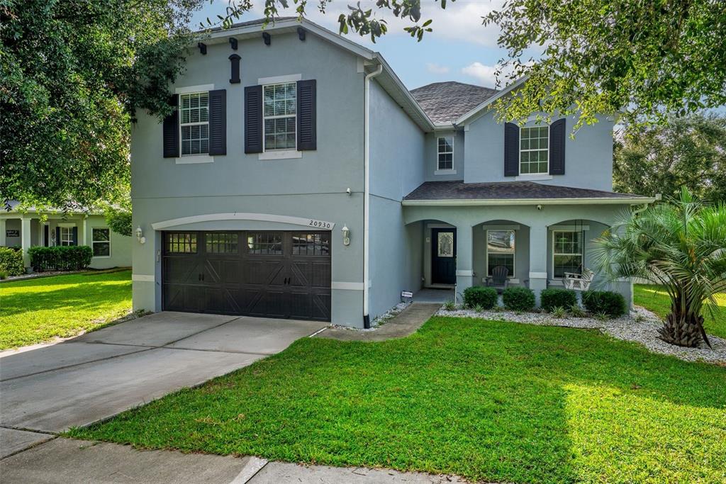 A two-story house with a gray stucco exterior, dark shutters, and a two-car garage — 20930 SULLIVAN RANCH BOULEVARD, MOUNT DORA, FL
