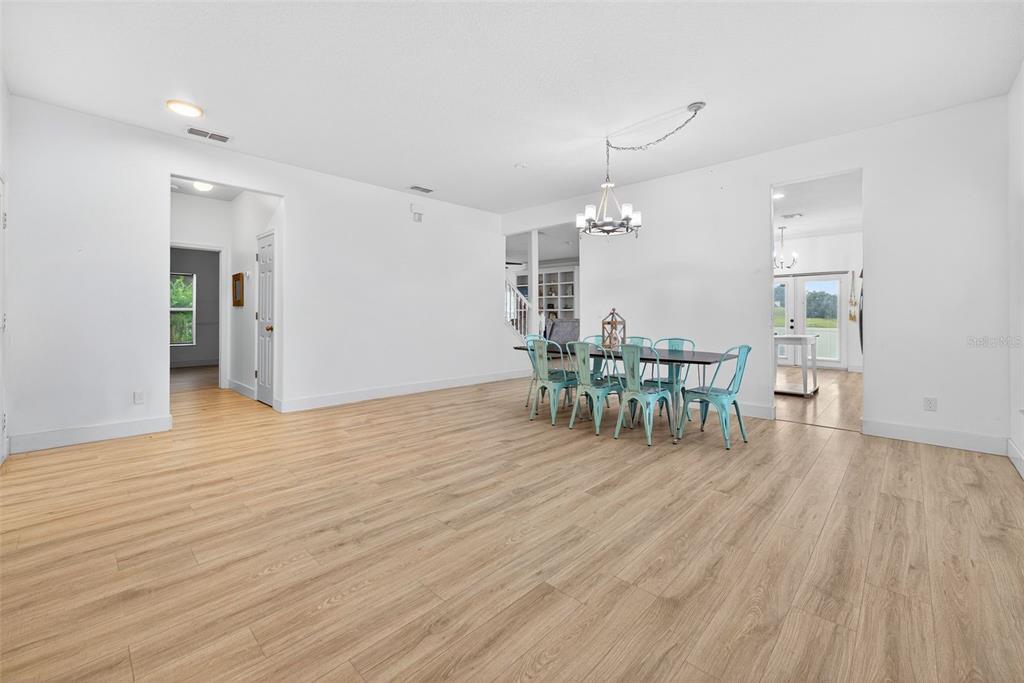 A dining area with light wood-look flooring, a chandelier, and a table with blue chairs — 20930 SULLIVAN RANCH BOULEVARD, MOUNT DORA, FL