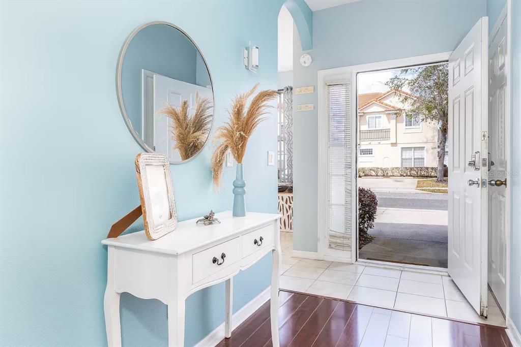 An entryway features a white console table, a round mirror, and an open front door — 1137 S BEACH CIRCLE, KISSIMMEE, FL