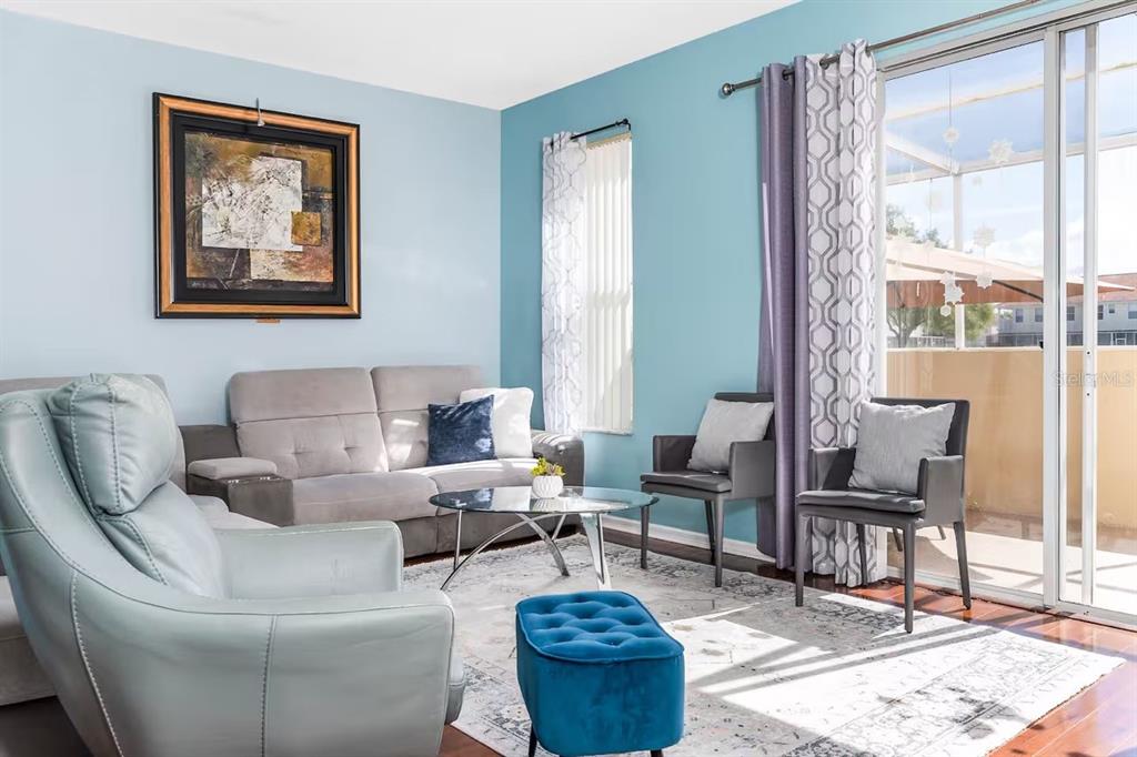 A living room features light blue walls, a grey sofa, a recliner, and a glass table — 1137 S BEACH CIRCLE, KISSIMMEE, FL