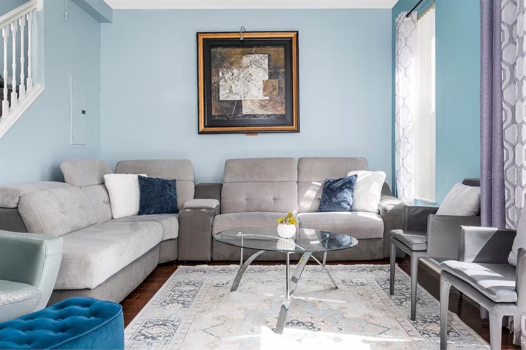 A living room features a gray sectional sofa, a glass coffee table, and blue accents — 1137 S BEACH CIRCLE, KISSIMMEE, FL