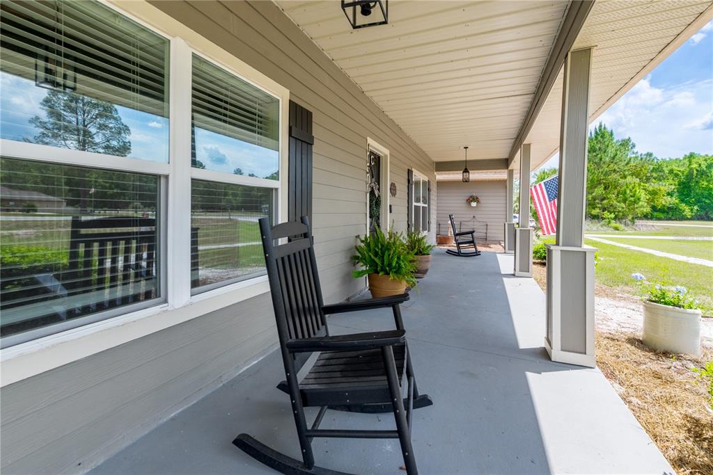 A gray house with a covered front porch, two rocking chairs, and a central entrance — 11311 NW 74TH COURT, CHIEFLAND, FL