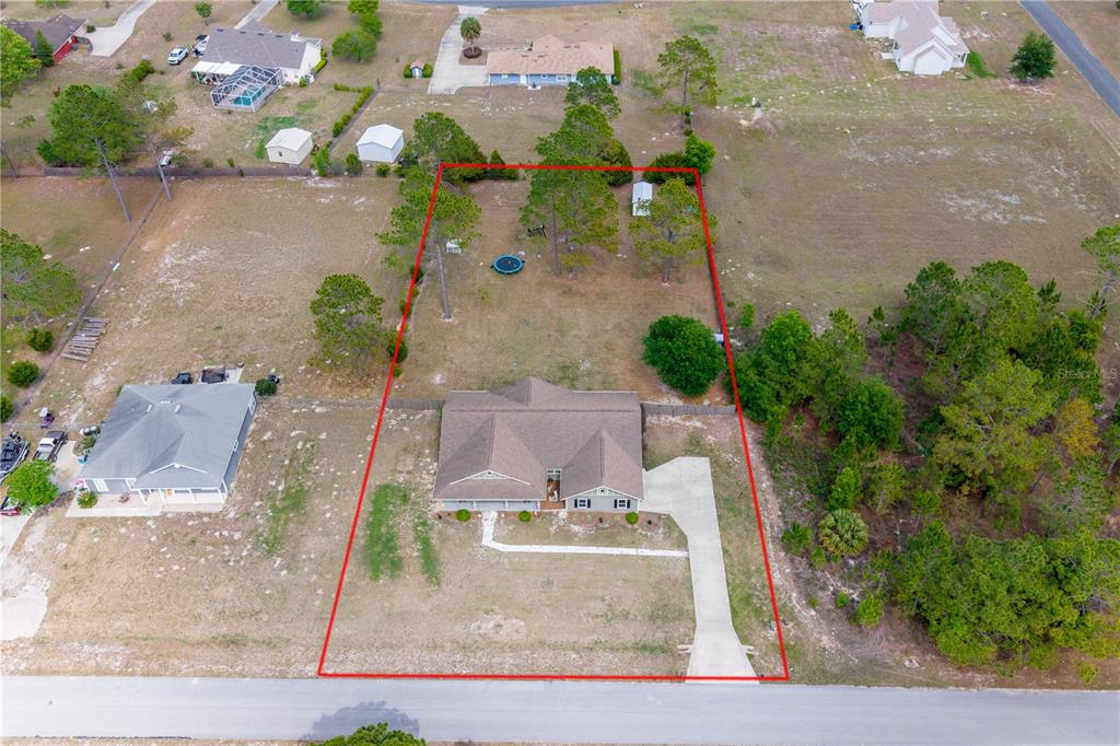 A covered front porch features gray siding, a concrete floor, and black rocking chairs — 11311 NW 74TH COURT, CHIEFLAND, FL