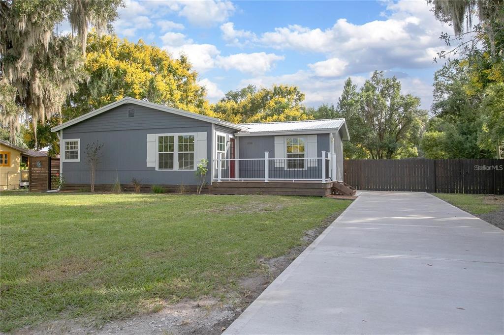 A gray single-story house features a front porch, white trim, and a concrete driveway — 1014 TALTON AVE, DELAND, FL