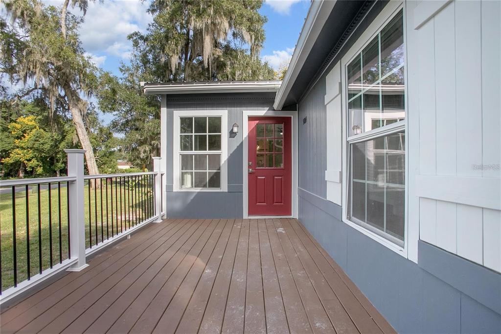 A wooden deck with a black railing leads to a red door on a house — 1014 TALTON AVE, DELAND, FL