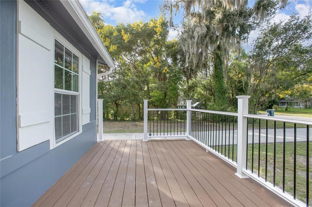 A wooden deck with white railings and black balusters overlooks a yard with mature trees — 1014 TALTON AVE, DELAND, FL