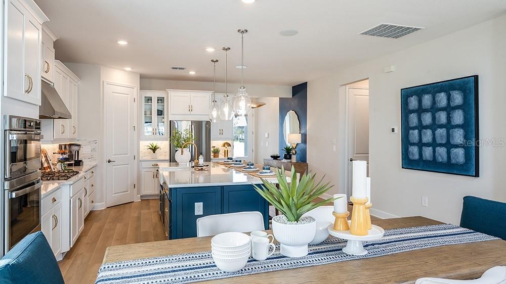 A kitchen with a blue island and white cabinets opens to a dining area — 10851 ECLIPSE STREET, SARASOTA, FL