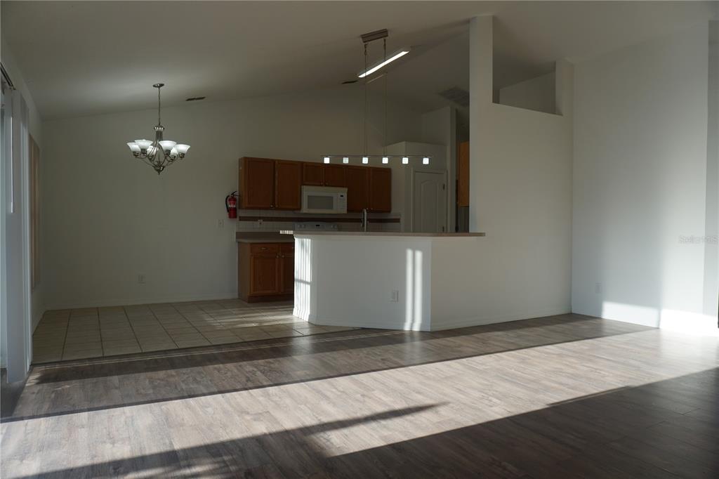 An open-concept kitchen with wood cabinets and a breakfast bar overlooks a living area — 10500 LAKE HASSON CIRCLE, CLERMONT, FL