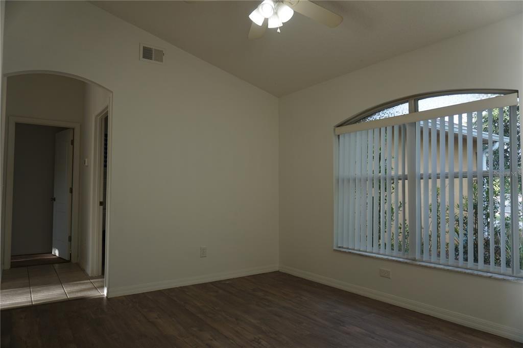 An empty bedroom features wood-look flooring, white walls, a ceiling fan, and a large arched window — 10500 LAKE HASSON CIRCLE, CLERMONT, FL