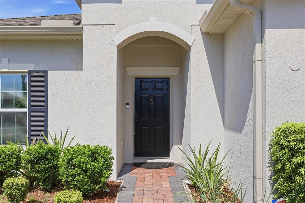 A black front door is centered under an arched entryway with a brick walkway — 601 BRIDGEFORD CROSSING BOULEVARD, DAVENPORT, FL