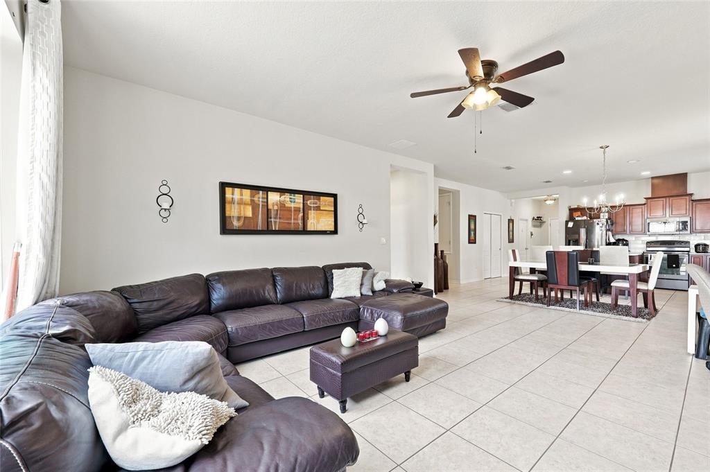 A living room with a large dark leather sectional, tile floors, and an open kitchen — 601 BRIDGEFORD CROSSING BOULEVARD, DAVENPORT, FL