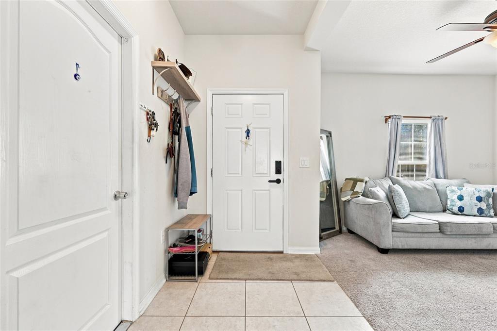An entryway with tile flooring leads to a living area featuring carpet and a sofa — 601 BRIDGEFORD CROSSING BOULEVARD, DAVENPORT, FL