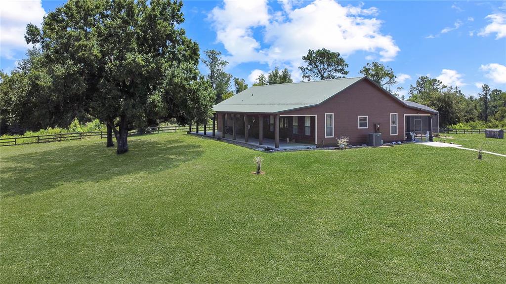A brown house with a green metal roof sits on a large, grassy lawn — 12150 SKYVIEW LANE UNIT 0, CLERMONT, FL