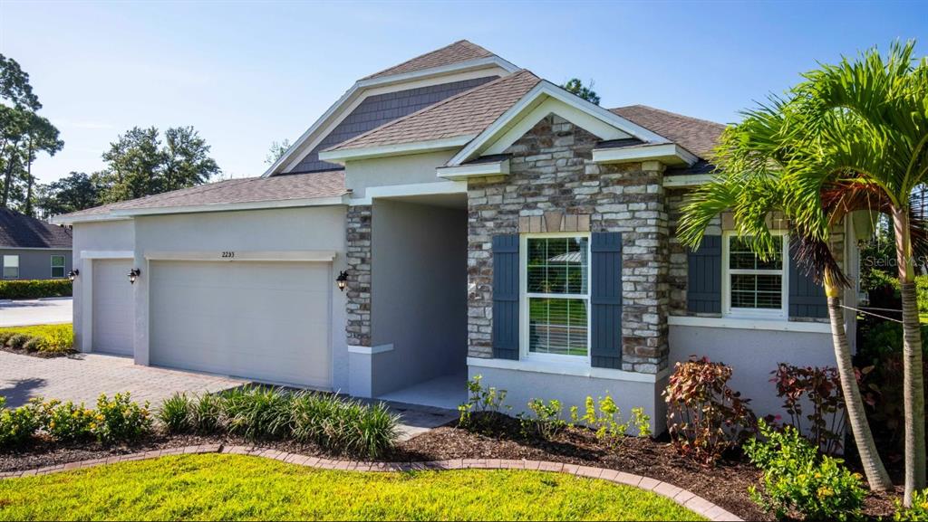 A single-story house exterior features a stone facade, a two-car garage, and a palm tree — 21 CUPANIA COURT, HOMOSASSA, FL