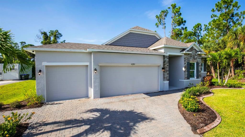 A single-story house with a two-car garage, stone accents, and a paved driveway — 21 CUPANIA COURT, HOMOSASSA, FL