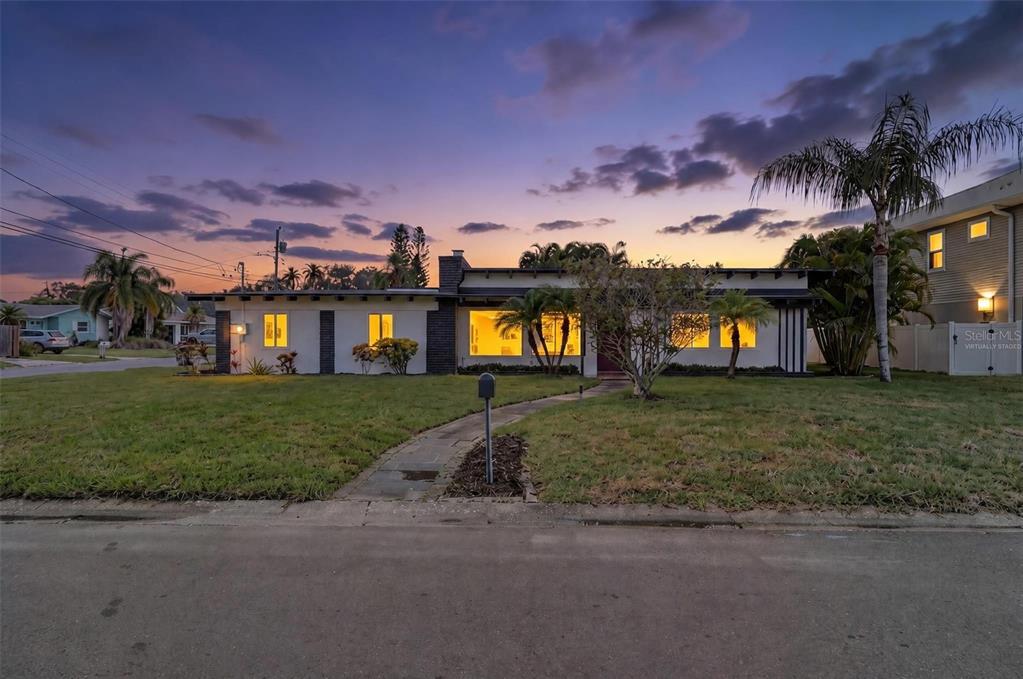 A single-story house with a carport and a large lawn under a sunset sky — 63 PALM BOULEVARD, DUNEDIN, FL