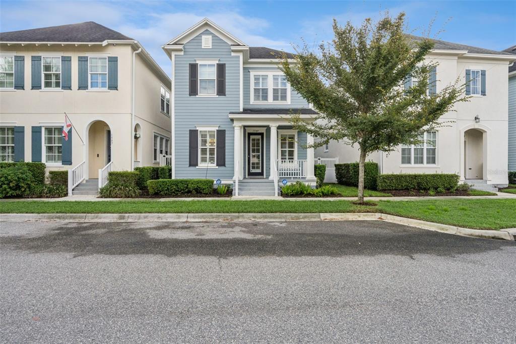 A blue two-story house with a front porch sits between two white houses — 1589 RESOLUTE STREET, CELEBRATION, FL