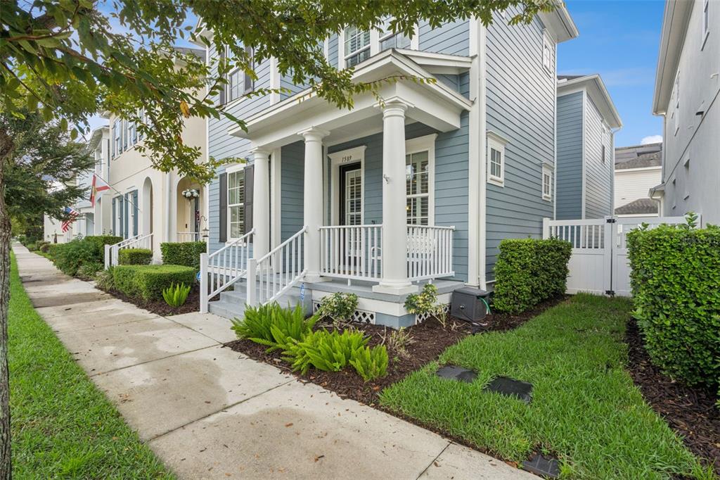 A blue two-story house with a white front porch, columns, and a sidewalk in front — 1589 RESOLUTE STREET, CELEBRATION, FL