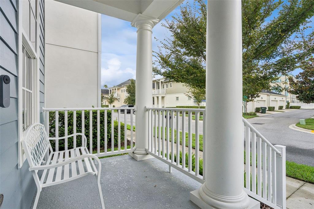 A white metal bench sits on a covered front porch with white columns and railings — 1589 RESOLUTE STREET, CELEBRATION, FL