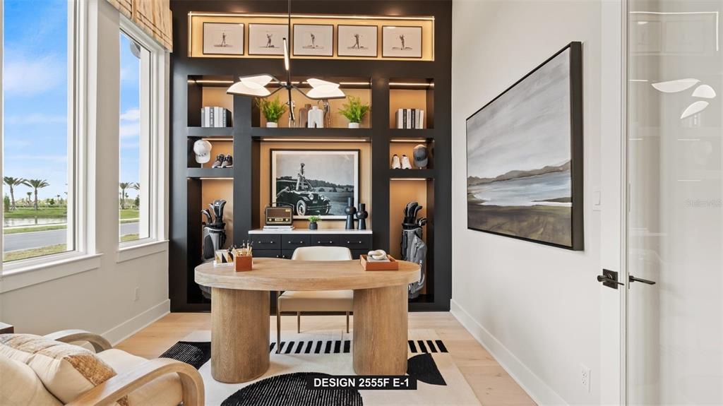 A home office features a wooden desk, built-in black shelving, and a large landscape painting — 9535 SANDY SHORES STREET, PARRISH, FL