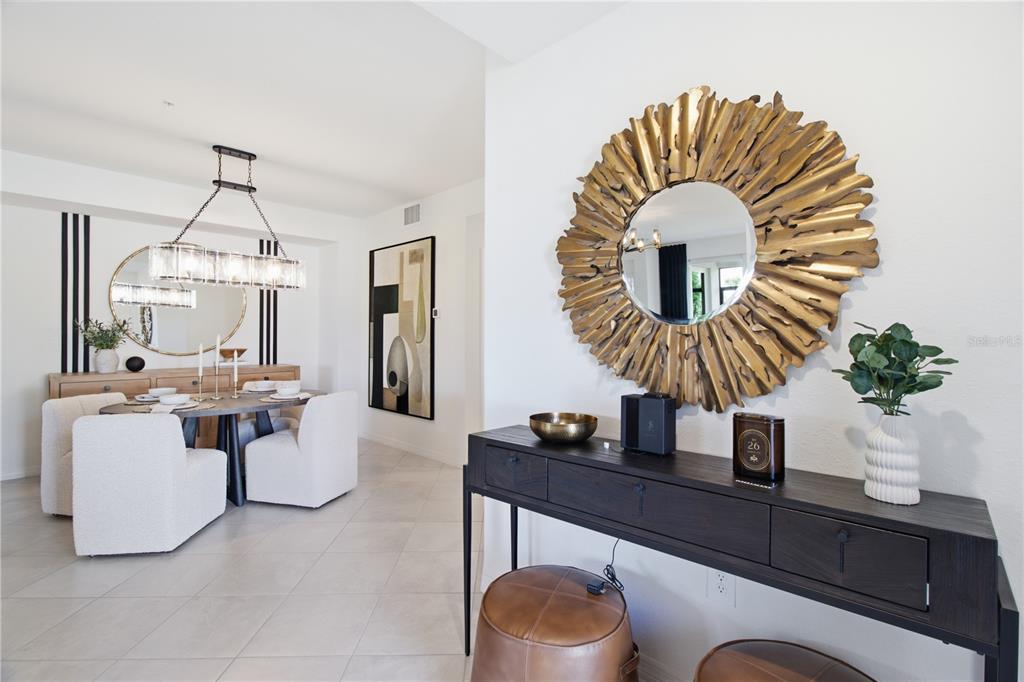 A dining room and entryway feature modern furniture, a sunburst mirror, and a console table — 19235 CHERRYSTONE WAY UNIT 101, LAKEWOOD RANCH, FL