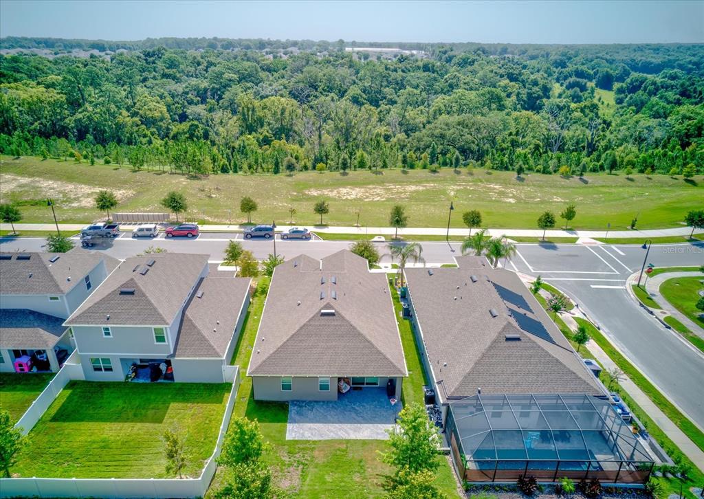 An aerial view shows three suburban houses with backyards, a street, and a wooded area — 2403 NATOMA BOULEVARD, MOUNT DORA, FL