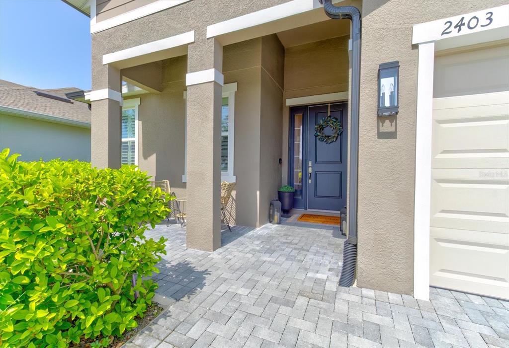 A paved front porch leads to a dark blue front door with a wreath — 2403 NATOMA BOULEVARD, MOUNT DORA, FL