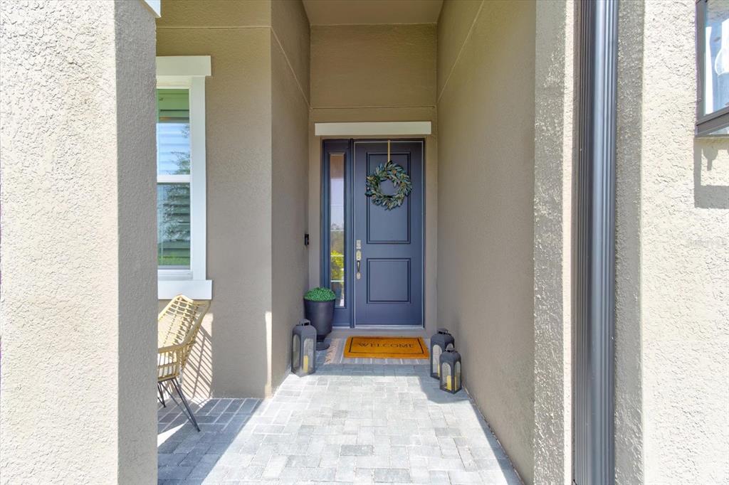 A covered entryway features a dark blue front door, a wreath, and a brick floor — 2403 NATOMA BOULEVARD, MOUNT DORA, FL