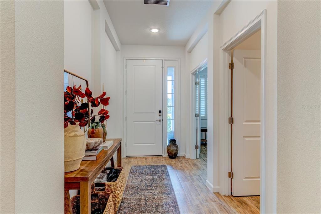 A bright entryway features a wood console table, a patterned runner, and a white door — 2403 NATOMA BOULEVARD, MOUNT DORA, FL