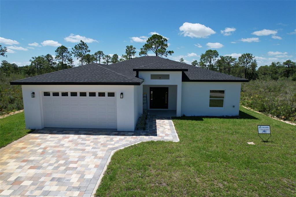 A modern single-story house with a white exterior, dark roof, and a paved driveway — 7435 CASILLA STREET, SEBRING, FL