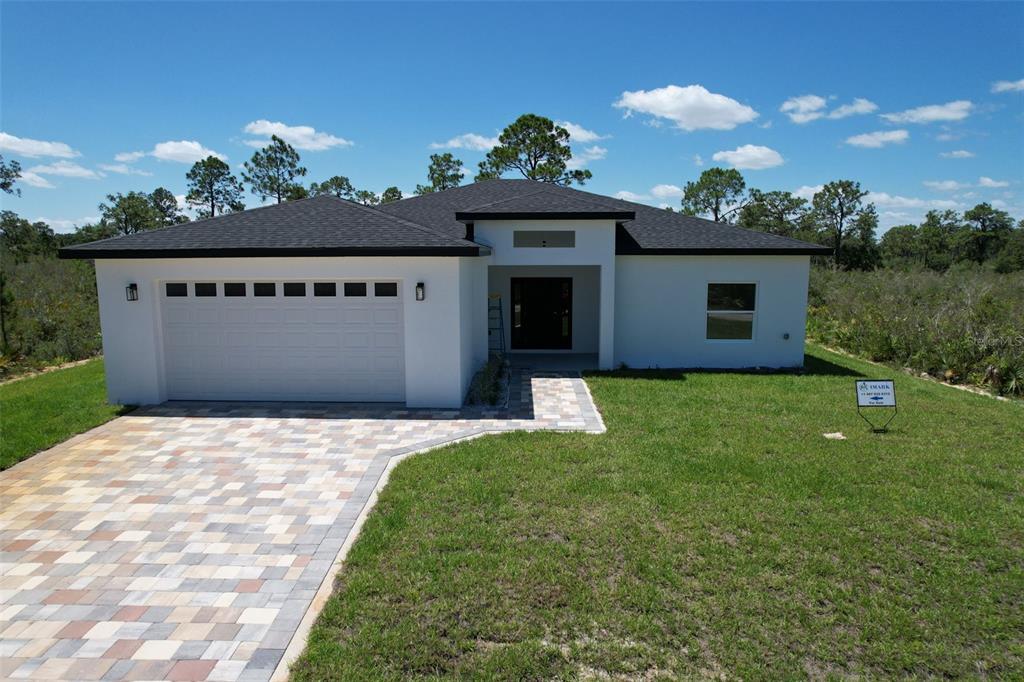 A single-story white house with a dark shingled roof and a paved driveway — 7435 CASILLA STREET, SEBRING, FL