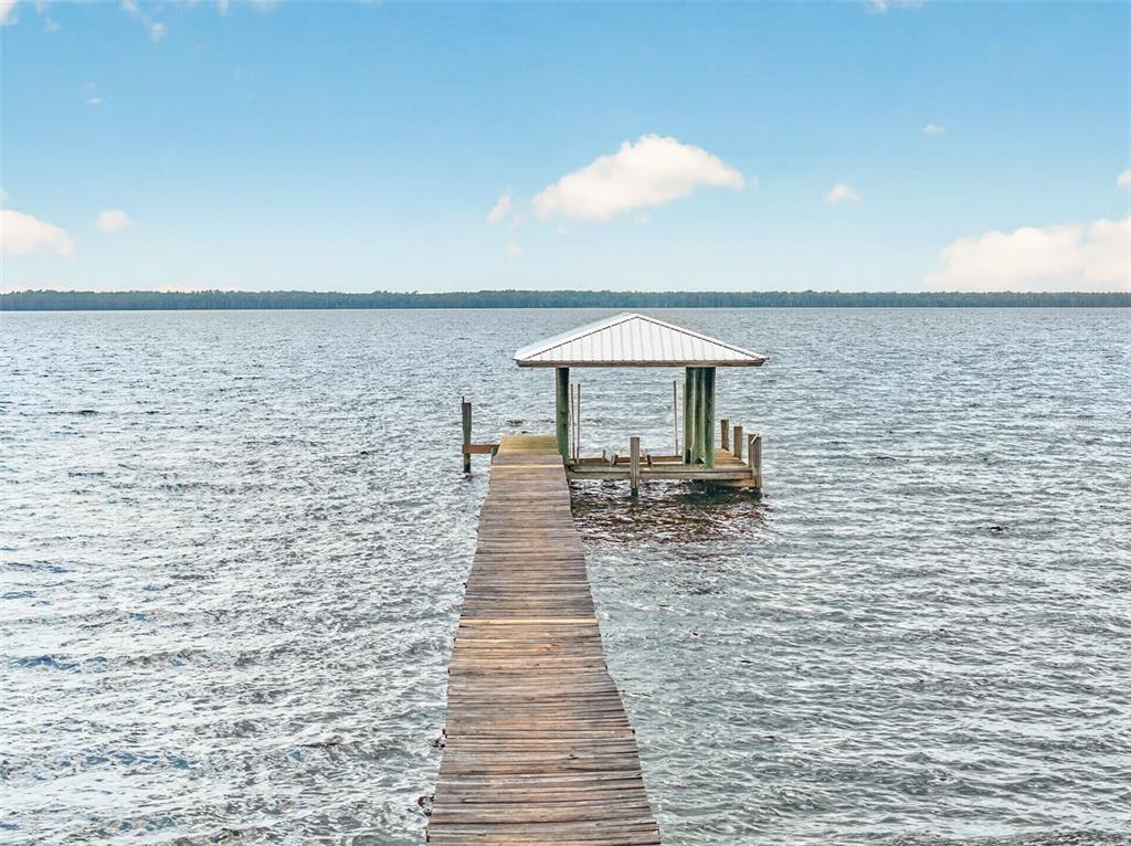 An aerial view shows a house nestled among trees along a large lakefront property — 6373 JACK WRIGHT ISLAND ROAD, ST AUGUSTINE, FL