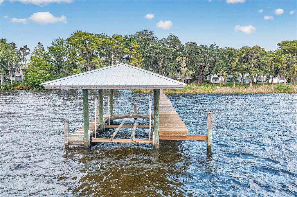 An aerial view shows a wooden dock extending into a lake toward a wooded shoreline — 6373 JACK WRIGHT ISLAND ROAD, ST AUGUSTINE, FL