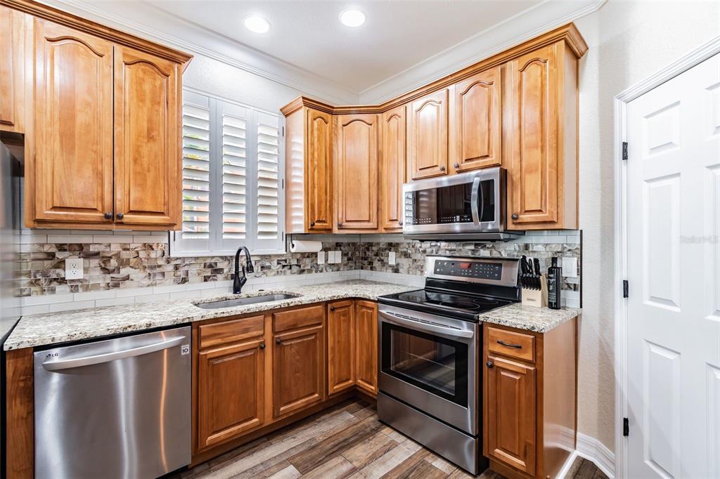 A kitchen features wood cabinets, granite countertops, stainless steel appliances, and a tiled backsplash — 539 TREVISO DRIVE, APOLLO BEACH, FL