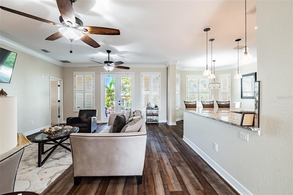 A living room and kitchen area with wood floors, ceiling fans, and a granite breakfast bar — 539 TREVISO DRIVE, APOLLO BEACH, FL