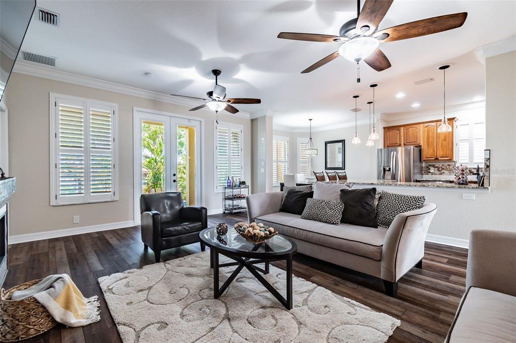 A living room with dark wood floors, a gray sofa, and an open-concept kitchen — 539 TREVISO DRIVE, APOLLO BEACH, FL