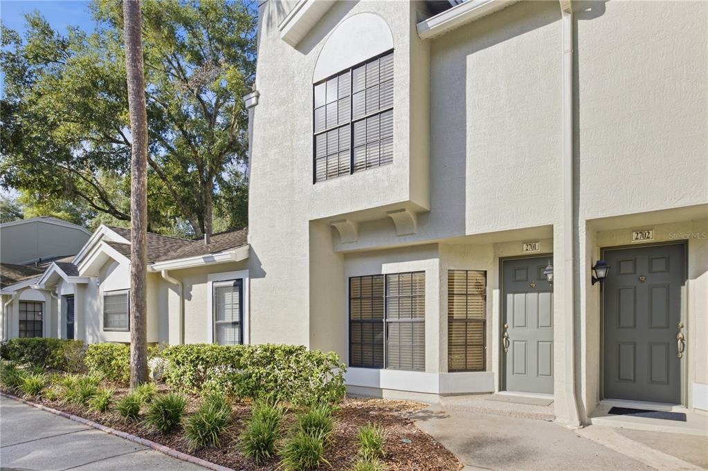 The exterior of two adjacent townhome units features beige stucco walls and dark gray doors — 5100 BURCHETTE ROAD UNIT 2701, TAMPA, FL