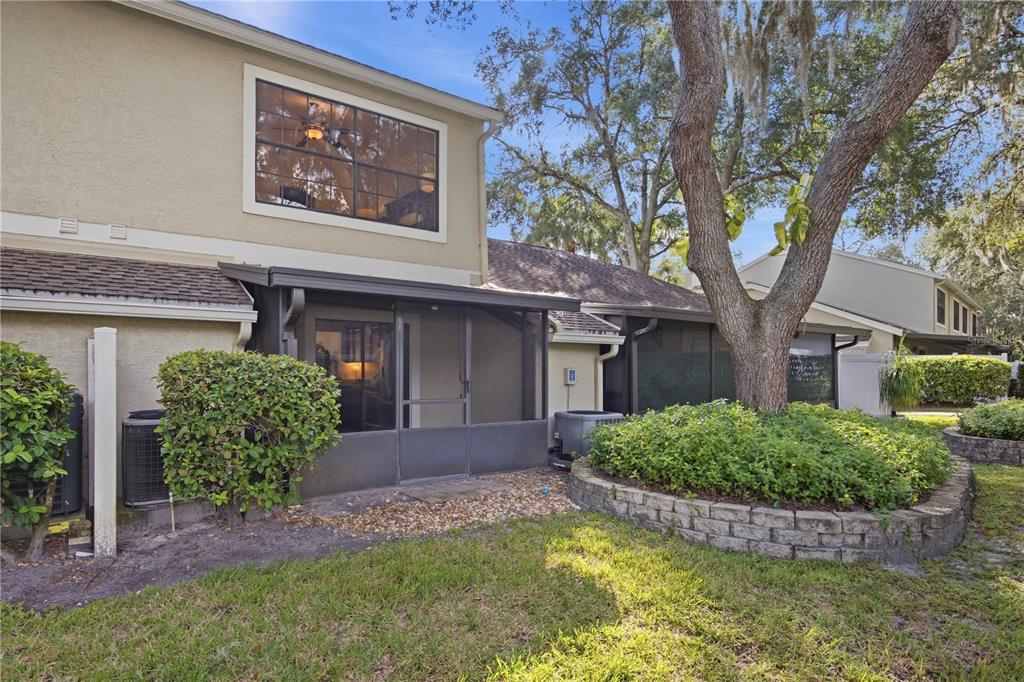 The exterior of a two-story home features a screened-in patio, landscaping, and a large tree — 5100 BURCHETTE ROAD UNIT 2701, TAMPA, FL