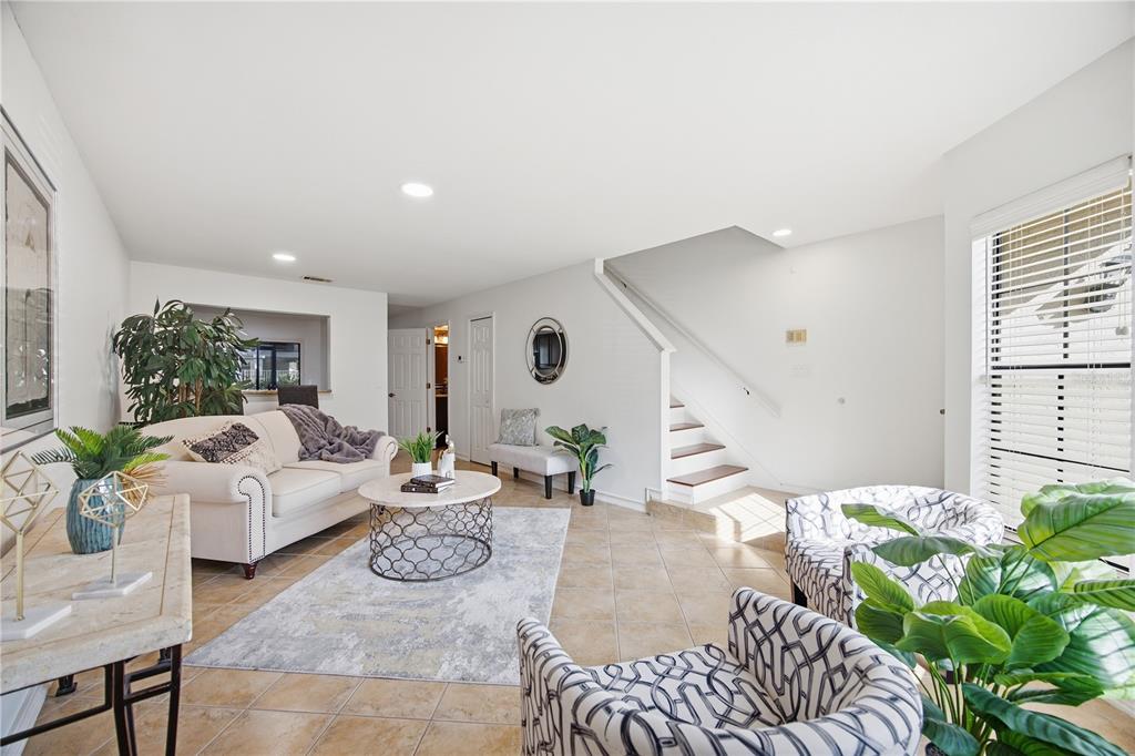 A living room with tile floors, a sofa, two patterned armchairs, and a staircase — 5100 BURCHETTE ROAD UNIT 2701, TAMPA, FL